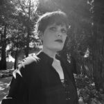 Tennell glancing upward in front of trees.