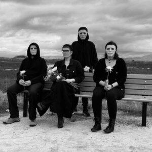 Tennell holding flowers and sitting on bench surrounded by three masked people.