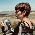 Close up of Tennell looking down at mirrored ball in her hands.